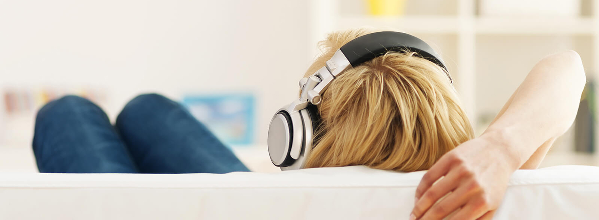 Person hört Musik mit Kopfhörern auf dem Sofa